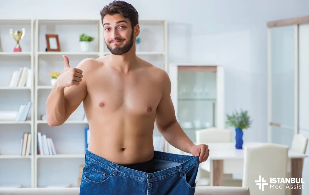 A skinny happy man is wearing his old baggy pants. Sleeve gastrectomy is a very effective method to eliminate excess weight that people cannot cope with.